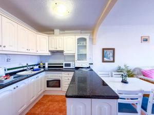 Una cocina con gabinetes blancos y una encimera negra. en Magnificent Balcon with Sea and Pool View, en Costa del Silencio