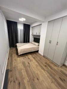 1 dormitorio con cama, armarios blancos y suelo de madera en Luxury, en Rădăuţi