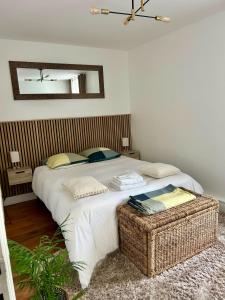 a bedroom with a large white bed with a wicker stool at Résidence Renan - Paris Porte de Versailles in Issy-les-Moulineaux +24 photos