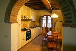 a kitchen with an archway and a table and chairs at Casale Rosanna in San Gimignano