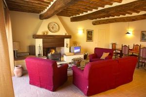 a living room with two red chairs and a fireplace at Casale Rosanna in San Gimignano