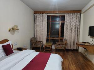 a hotel room with a bed and a window at Hotel Arohi in Vashisht