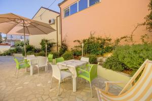a patio with tables and chairs and an umbrella at Apartment Jasna Near Čikat Bay and Center with Private Parking in Mali Lošinj