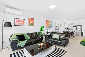 a living room with a leather couch and a dining room at Stylish 2br City Apartment Balcony&parking in Perth