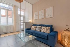 ein Wohnzimmer mit einem blauen Sofa und einem Glastisch in der Unterkunft Maison 3 chambres, parking gratuit & proche métro in Croix
