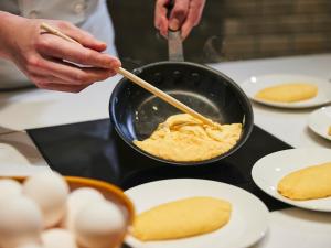 a person cooking food in a pan on a counter at Hotel Universal Port Vita in Osaka