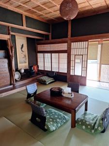 a living room with a wooden table and chairs at 古民家villa kobata in Bungotakada