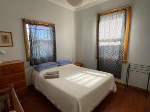 a bedroom with a bed and two windows at Cliff Cottage - Noraville in Norah Head