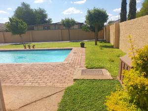 a swimming pool in a yard with grass and trees at Strand Meadows B&B in Gaborone