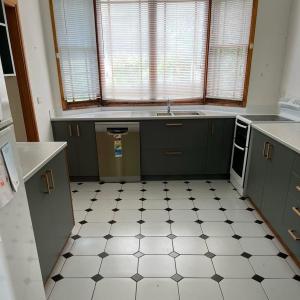 a kitchen with green cabinets and a white tiled floor at Cliff Cottage - Noraville in Norah Head +4 photos