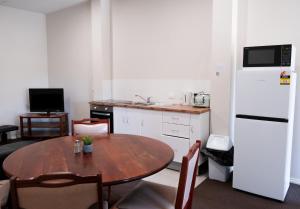 a kitchen with a table and a white refrigerator at Manjimup Gateway Hotel in Manjimup