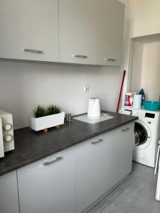 a kitchen with white cabinets and a washing machine at Apartament Piastowska in Gliwice