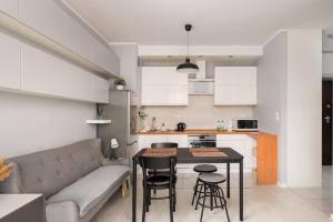 a living room and kitchen with a couch and a table at Bemowo Homely Apartment by BookingHost in Warszawa