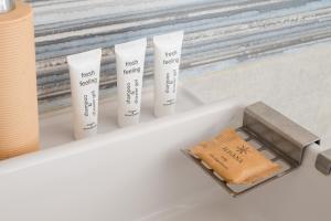 a white bathroom sink with four tubes of sunscreen at Bemowo Homely Apartment by BookingHost in Warszawa +14 photos