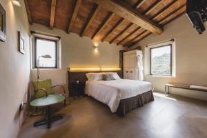 a bedroom with a bed and a chair and two windows at Torre di Baratti Bio Resort in Populonia