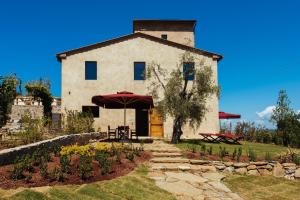 a building with a table and an umbrella in front of it at Torre di Baratti Bio Resort in Populonia