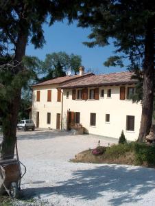 um grande edifício branco com uma árvore em frente em Agriturismo Macìn em Cesena