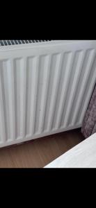 Un primer plano de un radiador blanco junto a una cama. en Zukz Haven, en Luton