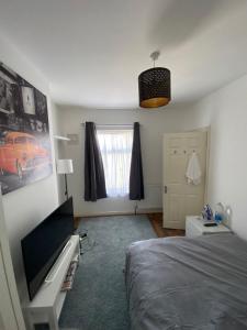 Un dormitorio con una cama y un escritorio y una ventana. en Zukz Haven, en Luton
