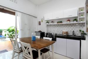 バンドンにあるVilla Normandieのキッチン(木製テーブル、白いキャビネット付)
