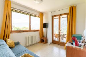 a living room with a blue couch and windows at Infinity View Garda lake in Tenno