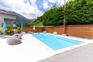 a swimming pool with chairs and umbrellas next to a house at Infinity View Garda lake in Tenno