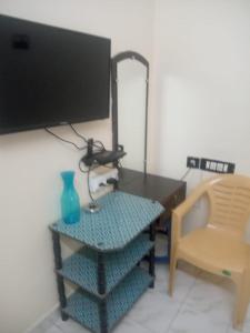 a room with a table with a tv and a chair at Suganya Lodge in Virudunagar