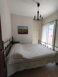 una camera da letto con un letto con un lampadario a braccio e una finestra di Thalassa Beach House, Marathonas-Aegina a Kapótidhes