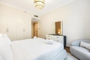 a white bedroom with a bed and a chair at Luxury 2BR Dubai Marina Apartment Walk to JBR Beach & Marina Yacht Club in Dubai