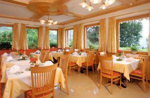 un restaurante con mesas y sillas blancas y ventanas en Garni Pluner, en Scena
