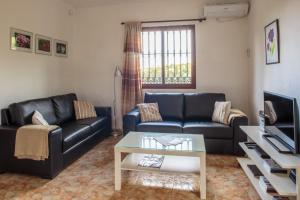 a living room with a black leather couch and a table at El Roble Holidays in Alhaurín el Grande