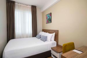 a hotel room with a white bed and a desk at TUI BLUE The Haven Ipoh in Ipoh