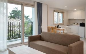 a living room with a couch and a kitchen at Hallim Resort in Jeju