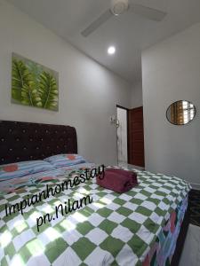 a bedroom with a bed with a checkeredkered bedspread at Impian homestay, wcy in Kota Bharu