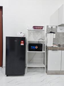 a black refrigerator in a kitchen with a shelf at Impian homestay, wcy in Kota Bharu +18 photos