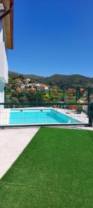 a swimming pool with green grass next to a building at Casa do Vale in Arcos de Valdevez