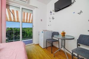 a room with a bed and a table and a television at Apartments and rooms Bionda in Senj
