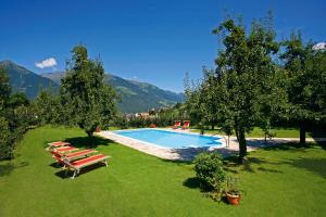 a swimming pool with lounge chairs and trees and mountains at Garni Pluner in Schenna