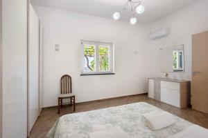 una camera da letto bianca con un letto e una sedia di Bella veduta Luna ad Agerola