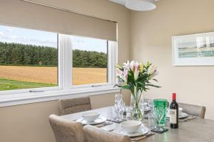 een tafel met een vaas met bloemen en een raam bij Muirton Cottage in Ardovie