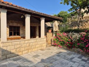 a house with a stone wall and flowers at Vetus pontem in Vrboska