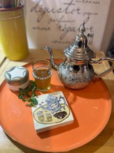 an orange plate with a tea pot and a drink at Lalla Rose in Lalla Takerkoust
