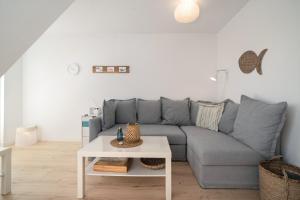 a living room with a gray couch and a table at Am Golfplatz 25 Strandkrabbe in Stakendorfer Strand