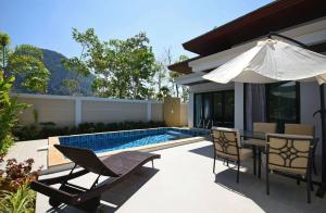 a patio with a table and chairs and an umbrella at Baan Ping Tara Tropical Pool Villa and Scooter in Ban Khlong Son