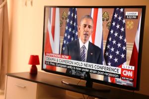 a television screen with a president talking in front of two american flags at Apartment 25B11 Mixta in Dakar