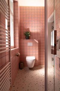 a pink tiled bathroom with a toilet and a potted plant at Hinterhaus Träumchen auf der Karl - Liebknecht in Leipzig