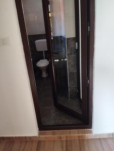 a bathroom with a toilet and a glass shower door at The sweet house! in Vama Veche