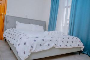 un letto in una camera con tende blu e finestra di Mama's Favourite ltd a Kigali