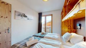 two beds in a room with a window at Pracondu 2 302 - OUTDOOR & FUN apartment 4 pers in Nendaz