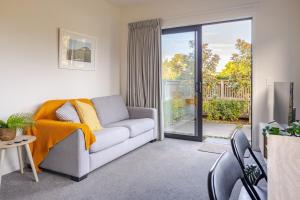 a living room with a couch and a sliding glass door at The Studio in Mount Maunganui